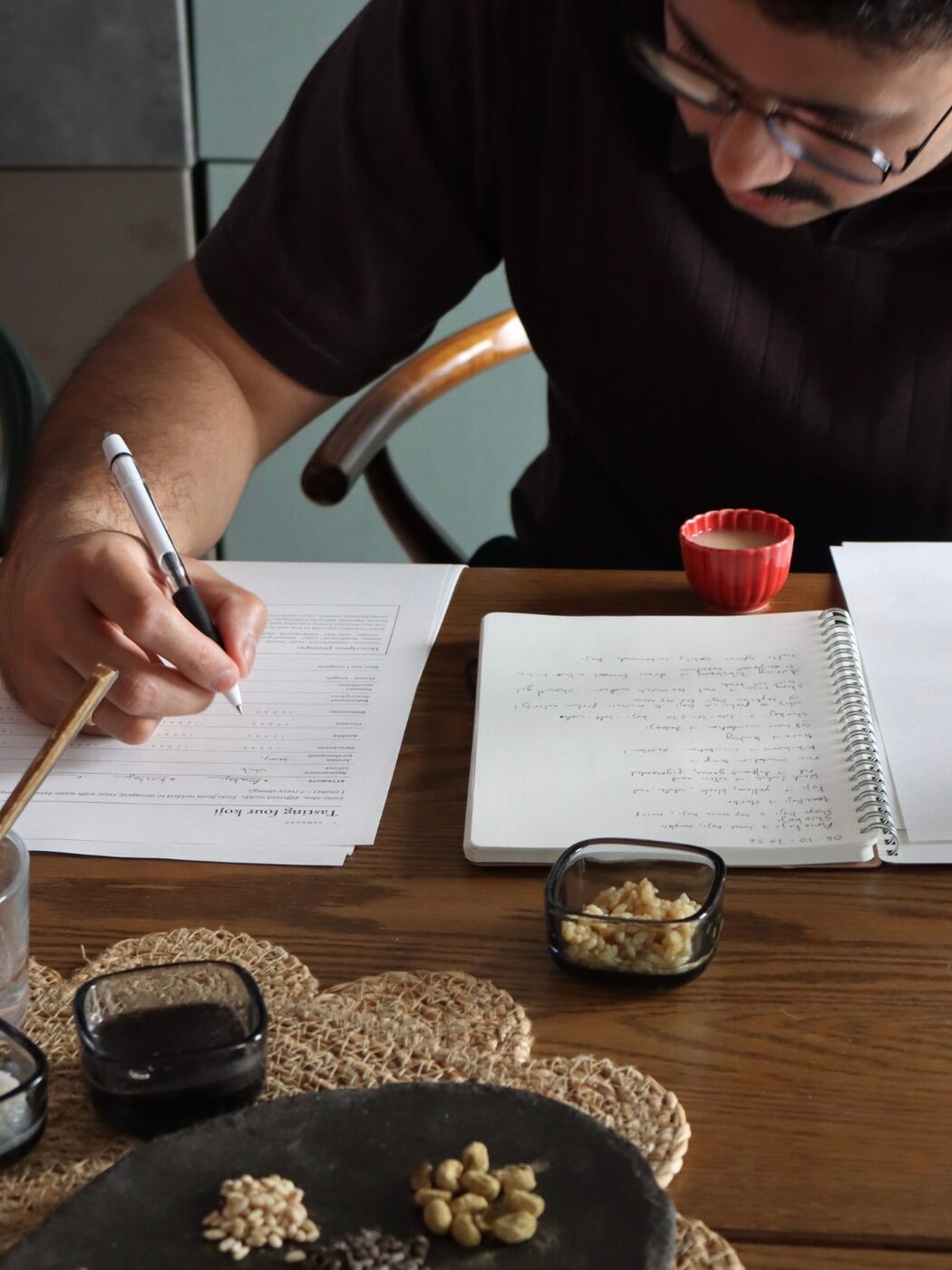 A guest writing tasting notes on koji at the kitchen table during UMAMI & KOJI LAB