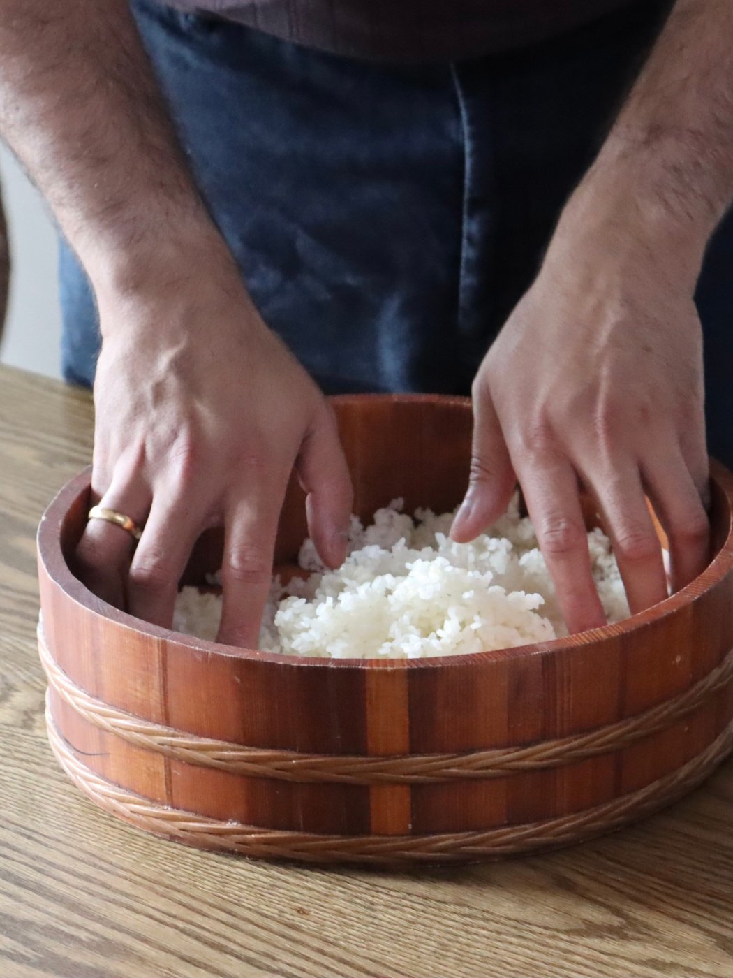 A guest working steamed rice by hand in a wooden tub during UMAMI & KOJI LAB