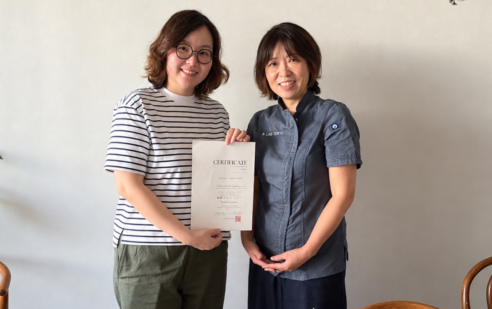 Joy holding her certificate, with Chie Ando