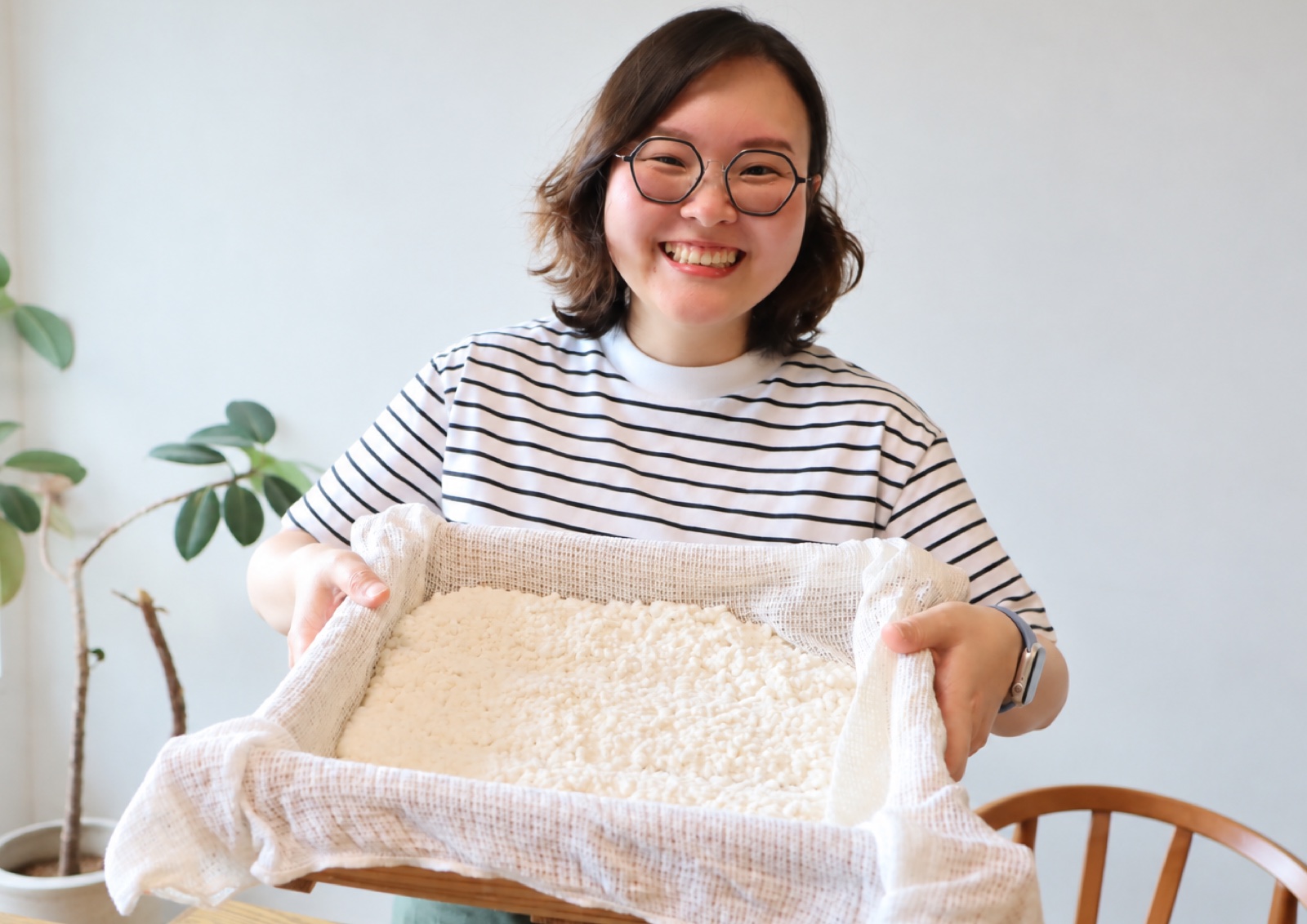 Joy holding a cloth-lined tray of steamed rice sown with tane-koji