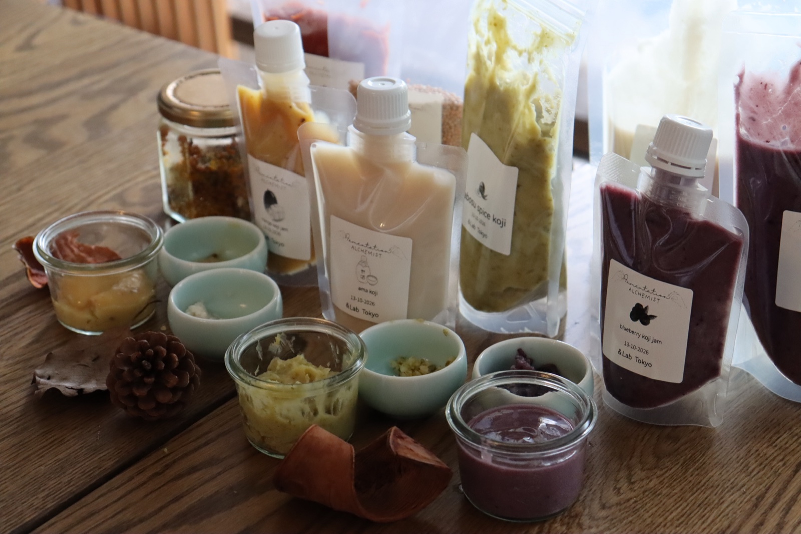 Pouches and jars of koji seasonings on the table: ama-koji, spice koji, blueberry koji jam and more