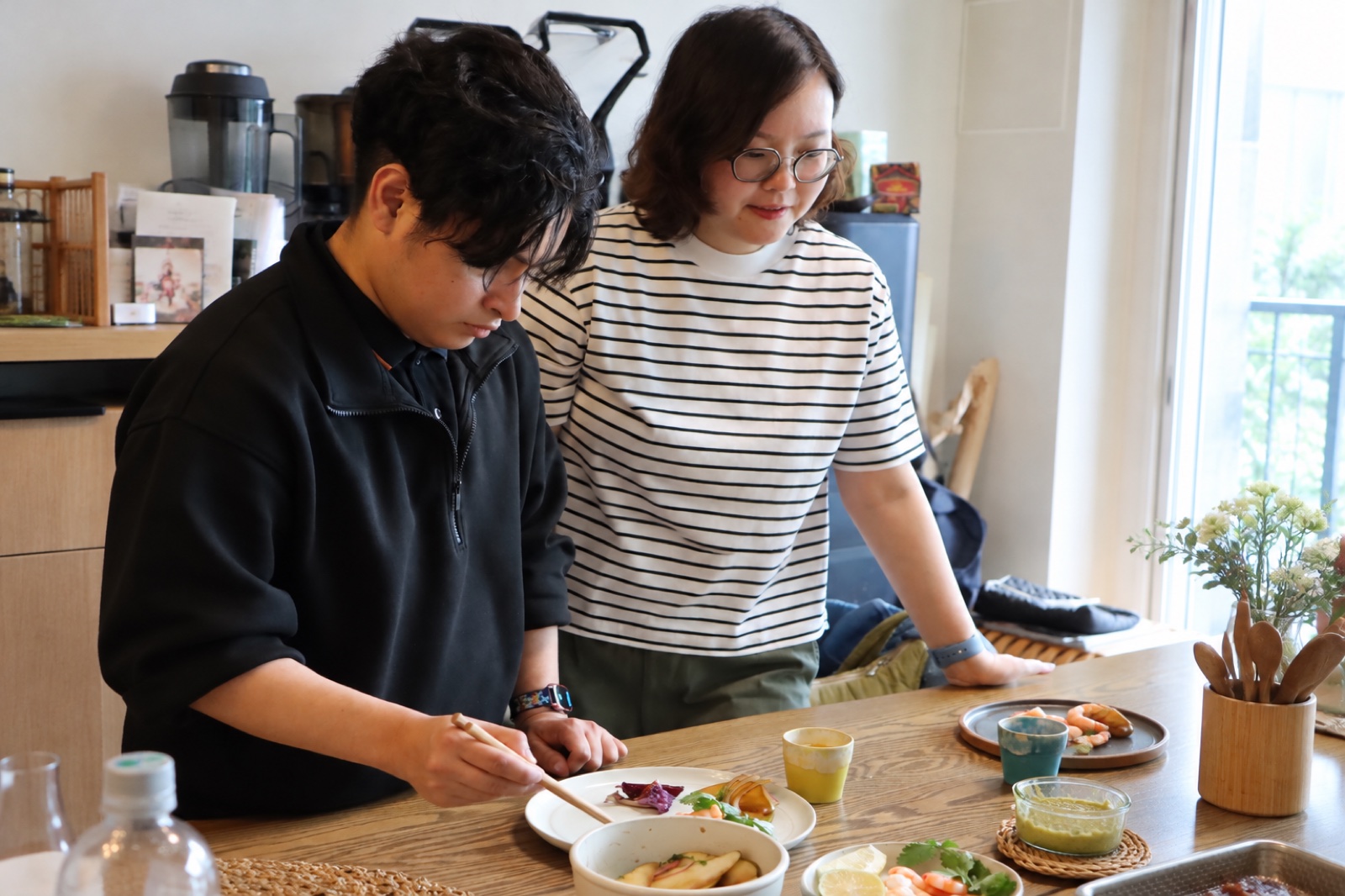 Joy watching our English-speaking assistant Chino plate a dish at the kitchen table