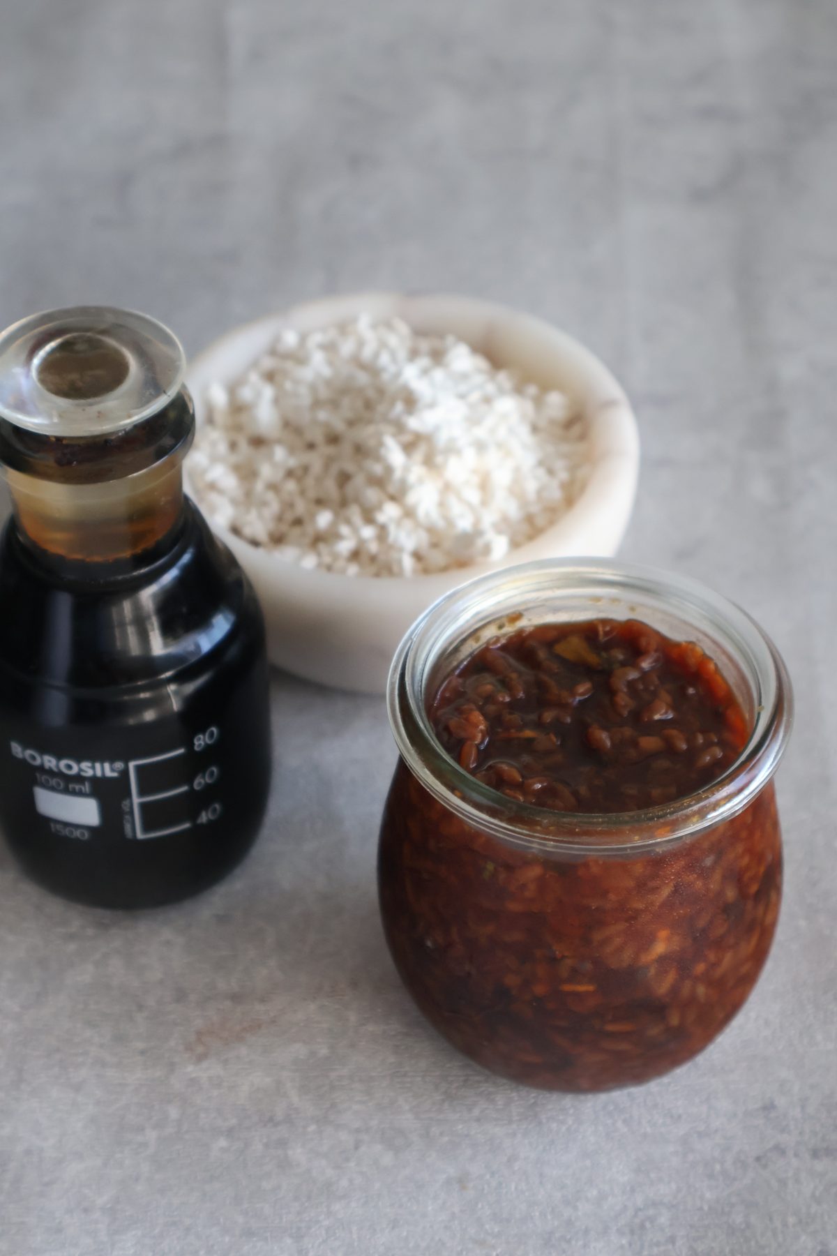 Shio-koji, shoyu-koji and a bottle of aged soy sauce on a dark table